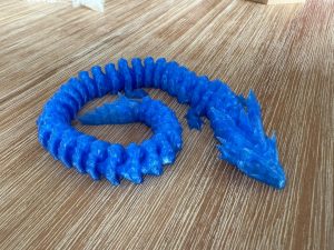 Skye the Sapphire Crystal Dragon articulated flexi dragon toy coiled on a table