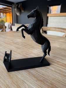 Black horse phone stand with rearing horse figurine on a wooden desk